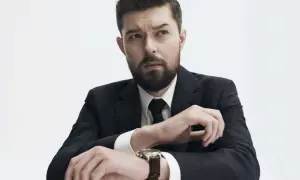 Mężczyzna w garniturze, z zarostem, zastanawia się, czy Remigiusz Mróz ma żonę.