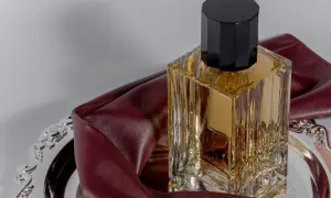 Elegancka butelka perfum na ozdobnej tacy, otulona bordową skórą. To wyjaśnia, dlaczego znana modelka nigdy nie używa tradycyjnych perfum z drogerii.