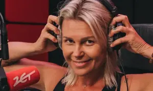 Agnieszka Kołodziejska, w wieku około 40 lat, z uśmiechem na twarzy zakłada słuchawki w studiu radiowym.