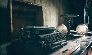 Stara maszyna do pisania w kufrze, obok lampka i ozdobne kule. Czy to tu gwiazdy piszą autobiografie z pomocą ghostwriterów?