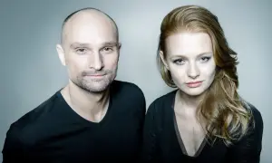 Dominik Strzelec i jego żona, uśmiechnięci, patrzą w obiektyw.