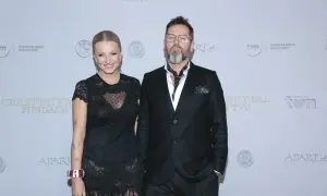 Michał Cessanis żona, ubrana w koronkową sukienkę, pozuje obok męża w eleganckim garniturze.