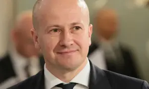 Uśmiechnięty mężczyzna w garniturze, być może partner popularnej aktorki, który zrezygnował z kariery dla niej.