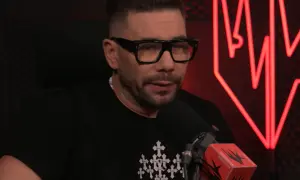 Mężczyzna w okularach i czarnej koszulce z krzyżami, kto prowadzi szalony podcast.