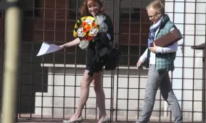 Sebastian Parfjanowicz i Justyna Kowalczyk idą obok siebie. Ona trzyma bukiet kwiatów i dokumenty, on niesie drewniane pudełko.
