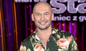 Tomasz z "Tańca z Gwiazdami" w kwiecistej koszuli, uśmiechnięty na tle sceny.