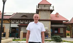 Mężczyzna w koszulce z logo Energylandii, prawdopodobnie właściciel, stoi przed budynkiem parku rozrywki.