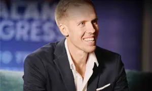 Uśmiechnięty mężczyzna, Dawid Piątkowski, w eleganckim garniturze. Wiek nie jest widoczny, ale jego energia jest wyczuwalna.