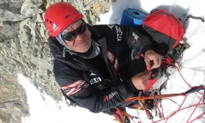 Alpinista w kasku i okularach, który nie ma lęku wysokości, przygotowuje sprzęt na dachu świata.