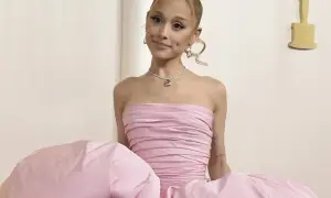 Ariana Grande w różowej sukni, z naszyjnikiem. Ciekawe, ile lat ma Ariana Grande, gdy nosi taką kreację.