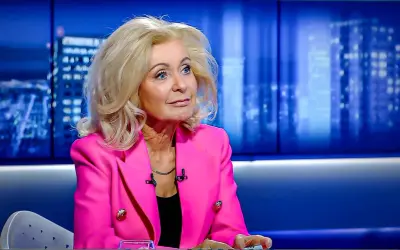 Kobieta w różowej marynarce, z blond włosami, siedzi w studiu. Ile lat ma Krystyna Hołc? Trudno zgadnąć, wygląda świetnie!