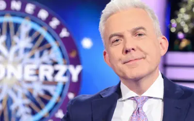 Hubert Urbański w garniturze i krawacie, na tle koła z napisem "Milionerzy". Czy to jego ostatnie chwile w programie i dlaczego znana dziennikarka przeszła do konkurencji bez pożegnania z widzami?