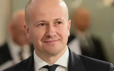 Uśmiechnięty mężczyzna w garniturze, być może partner popularnej aktorki, który zrezygnował z kariery dla niej.