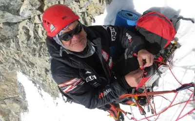 Alpinista w kasku i okularach, który nie ma lęku wysokości, przygotowuje sprzęt na dachu świata.