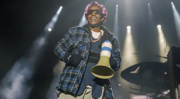 Raper A$AP Rocky, z wałkami na włosach i w kratowanej koszuli, śmieje się na scenie. Czy asap rocky żyje? Tak, i to w świetnej formie!