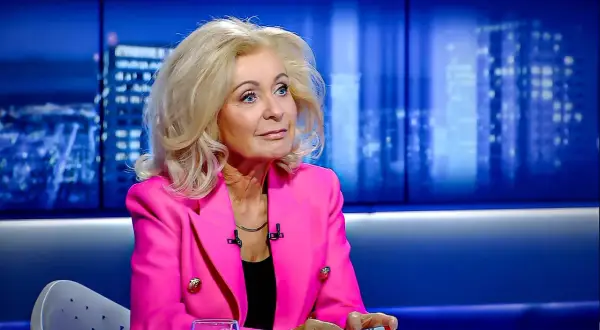 Kobieta w różowej marynarce, z blond włosami, siedzi w studiu. Ile lat ma Krystyna Hołc? Trudno zgadnąć, wygląda świetnie!