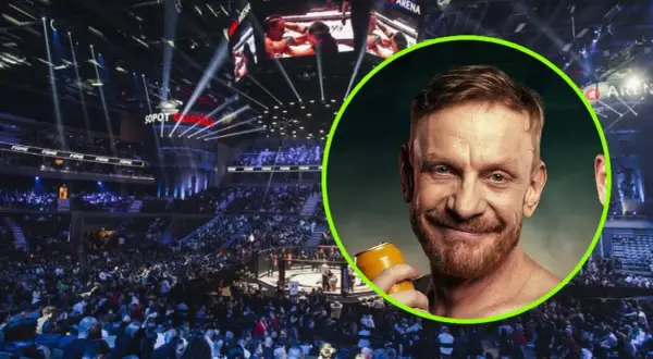 Tomasz Matysiak z puszką piwa na tle hali widowiskowej z widownią i ringiem.