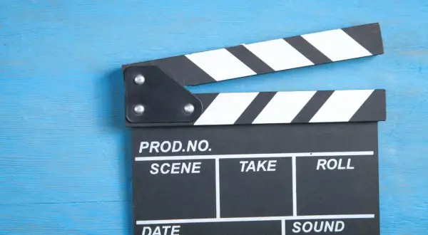 Klapka filmowa na niebieskim tle. Zastanawiasz się, ile zarabiają polscy aktorzy za jeden dzień zdjęciowy w hicie kinowym?