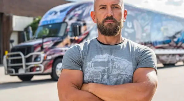 Dawid Andres, w sile wieku, z brodą, stoi przed ozdobioną ciężarówką.