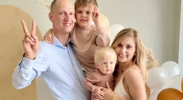 Katarzyna z mężem i dziećmi, uśmiechnięci, w otoczeniu balonów.