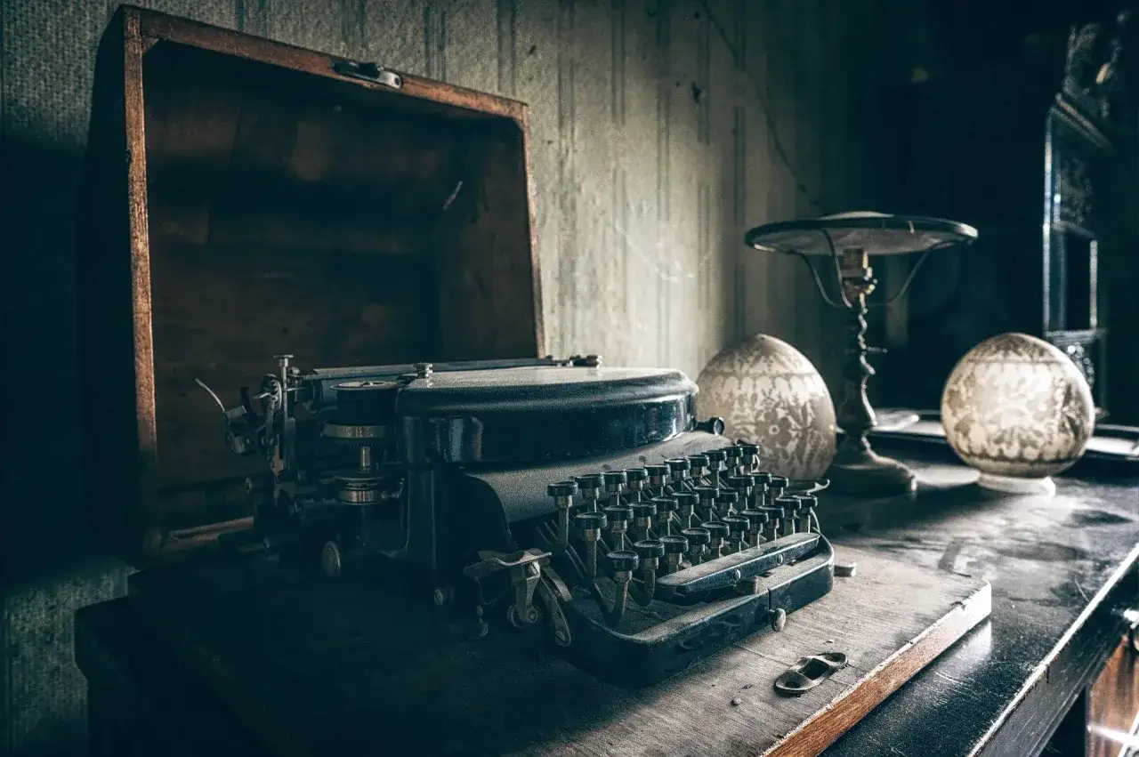 Stara maszyna do pisania w kufrze, obok lampka i ozdobne kule. Czy to tu gwiazdy piszą autobiografie z pomocą ghostwriterów?