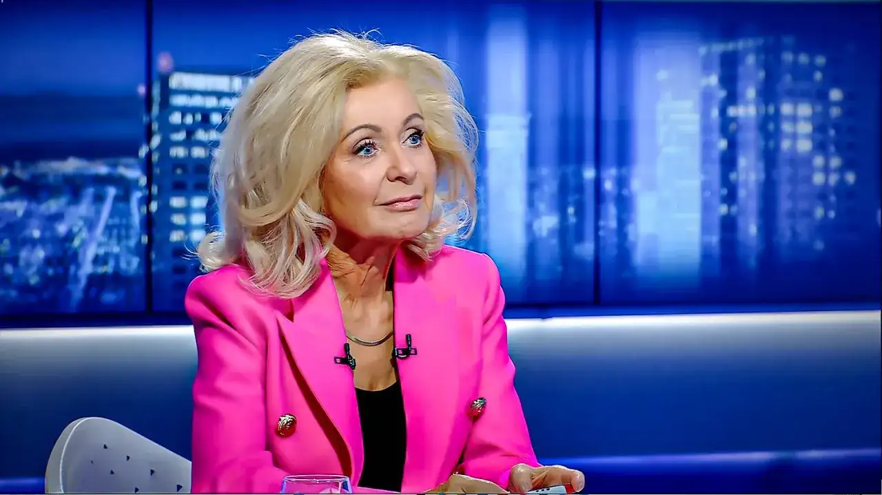 Kobieta w różowej marynarce, z blond włosami, siedzi w studiu. Ile lat ma Krystyna Hołc? Trudno zgadnąć, wygląda świetnie!