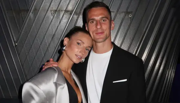 Agata Sieramska i jej partner pozują do zdjęcia. Ona ma na sobie srebrną marynarkę i dużą, metaliczną biżuterię.