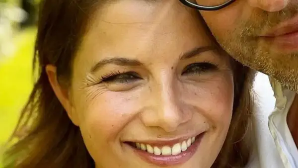 Agnieszka Sienkiewicz uśmiecha się, przytulona do swojego męża, który ma zarost i okulary.