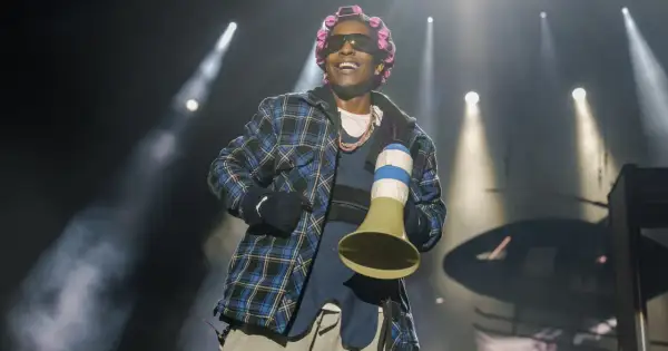 Raper A$AP Rocky, z wałkami na włosach i w kratowanej koszuli, śmieje się na scenie. Czy asap rocky żyje? Tak, i to w świetnej formie!