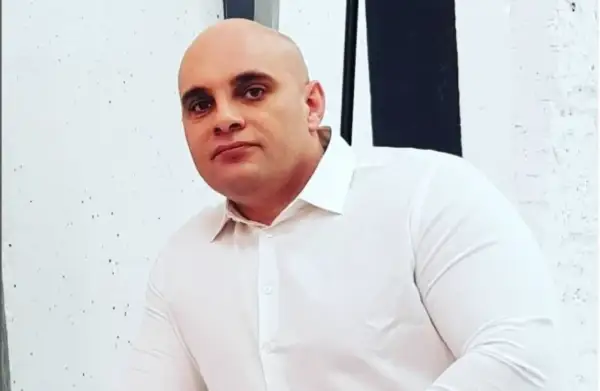 Dominik Abus, wiek nieznany, w białej koszuli, na tle białej ściany z czarnymi pasami.